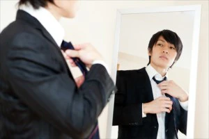 鏡に向かってネクタイを締める人