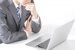 PCの前で悩むスーツ姿の男性