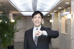 時計を確認して笑うビジネスマン